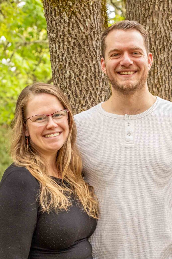 A couple standing in front a tree.